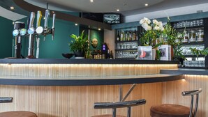 Una zona de bar con mostrador, varias llaves de cerveza y tres taburetes.
