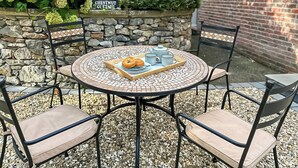 A round outdoor table with a tray of food and tea cups, surrounded by four chairs, set against a stone wall and greenery. - 2 bedroom accommodation in Coxley Wick, near Wells (Coxley Wick, near Wells)