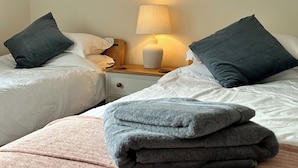 A hotel room with two beds, each with a pillow and a bedside table with a lamp. - 2 bedroom accommodation in Coxley Wick, near Wells (Coxley Wick, near Wells)