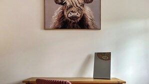 A framed artwork of a yak on a wall, a wooden desk with drawers, and a vase with a decorative lid. - 2 bedroom accommodation in Coxley Wick, near Wells (Coxley Wick, near Wells)