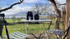 Un área de estar al aire libre con una mesa y sillas, con vistas a un paisaje pintoresco.
