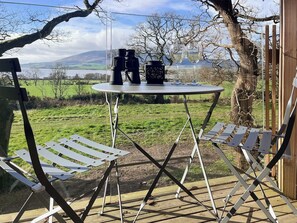 An outdoor seating area with a table and chairs, overlooking a scenic landscape.