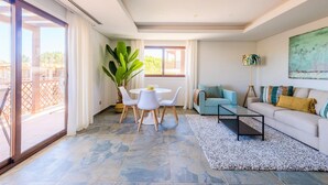 A modern living room with a glass coffee table, a sofa, and a dining table with chairs. - Falesia Beach C at Falesia Beach (Albufeira)