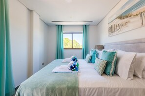 Ein Schlafzimmer mit einem Bett, einem Fenster mit Vorhängen und einem Bild an der Wand.