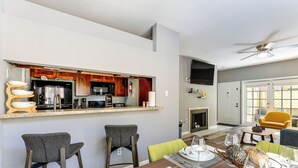 Una cucina moderna con angolo bar, un tavolo da pranzo per quattro persone e un soggiorno con divano e poltrone.