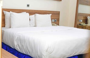 Una cama bien hecha con ropa blanca y un cabecero de madera.