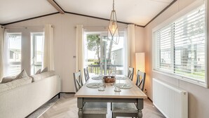 Un espace repas comprenant une table en bois, des chaises et un luminaire suspendu.