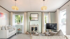 Un salon comprenant un canapé, un téléviseur, une cheminée et deux lampes suspendues.