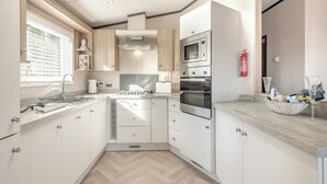 Une cuisine moderne dotée d’une verrière, d’appareils électroménagers intégrés et d’un parquet en bois disposé en chevrons.