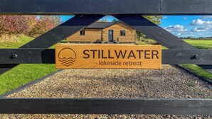 Un panneau en bois indiquant « STILLWATER, lieu de villégiature au bord du lac », ainsi qu’un symbole représentant un soleil et des vagues.