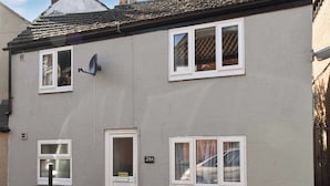 Une maison à deux étages avec une porte blanche, une antenne parabolique et une plaque d’immatriculation portant le numéro « 24A ».