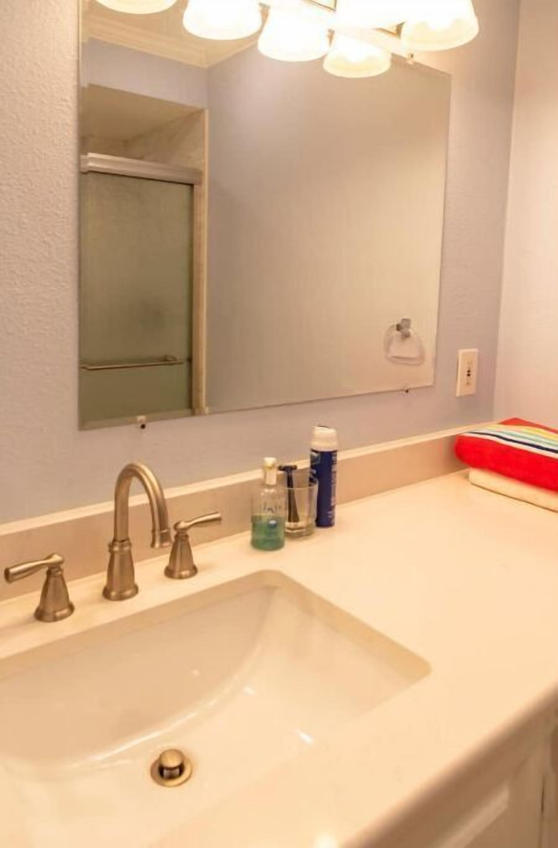 A bathroom with a white sink, a mirror, and a towel rack.