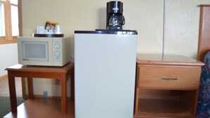Una kitchenette compacta con microondas, refrigerador y cafetera sobre una pequeña mesa.