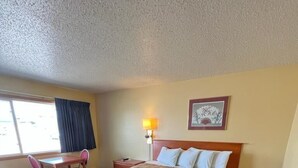 Una habitación de hotel con una cama, un escritorio y una silla.