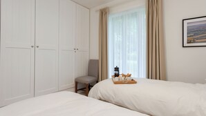 A bedroom with two beds, a chair, a bedside table with a tray, and a large wardrobe. - 3 bedroom accommodation in Beauworth, near Alresford (Beauworth, near Alresford)