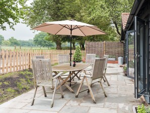An outdoor patio with a table and chairs, a large umbrella, and a wooden fence.