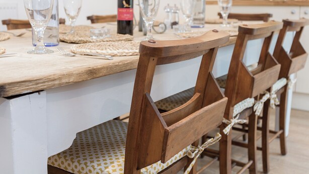A wooden dining table set with glassware and a bottle, surrounded by wooden chairs with a woven placemat. - 3 bedroom accommodation in Beauworth, near Alresford (Beauworth, near Alresford)