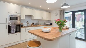 A modern kitchen with white cabinets, a wooden countertop, a built-in oven, a microwave, and a large window with a view of the outside. - 3 bedroom accommodation in Beauworth, near Alresford (Beauworth, near Alresford)
