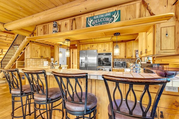 A wooden interior with a kitchen, bar stools, and a sign reading 'WELCOME.' - "Rustic Elegance - A Woodland Escape" (Idyllwild-Pine Cove)