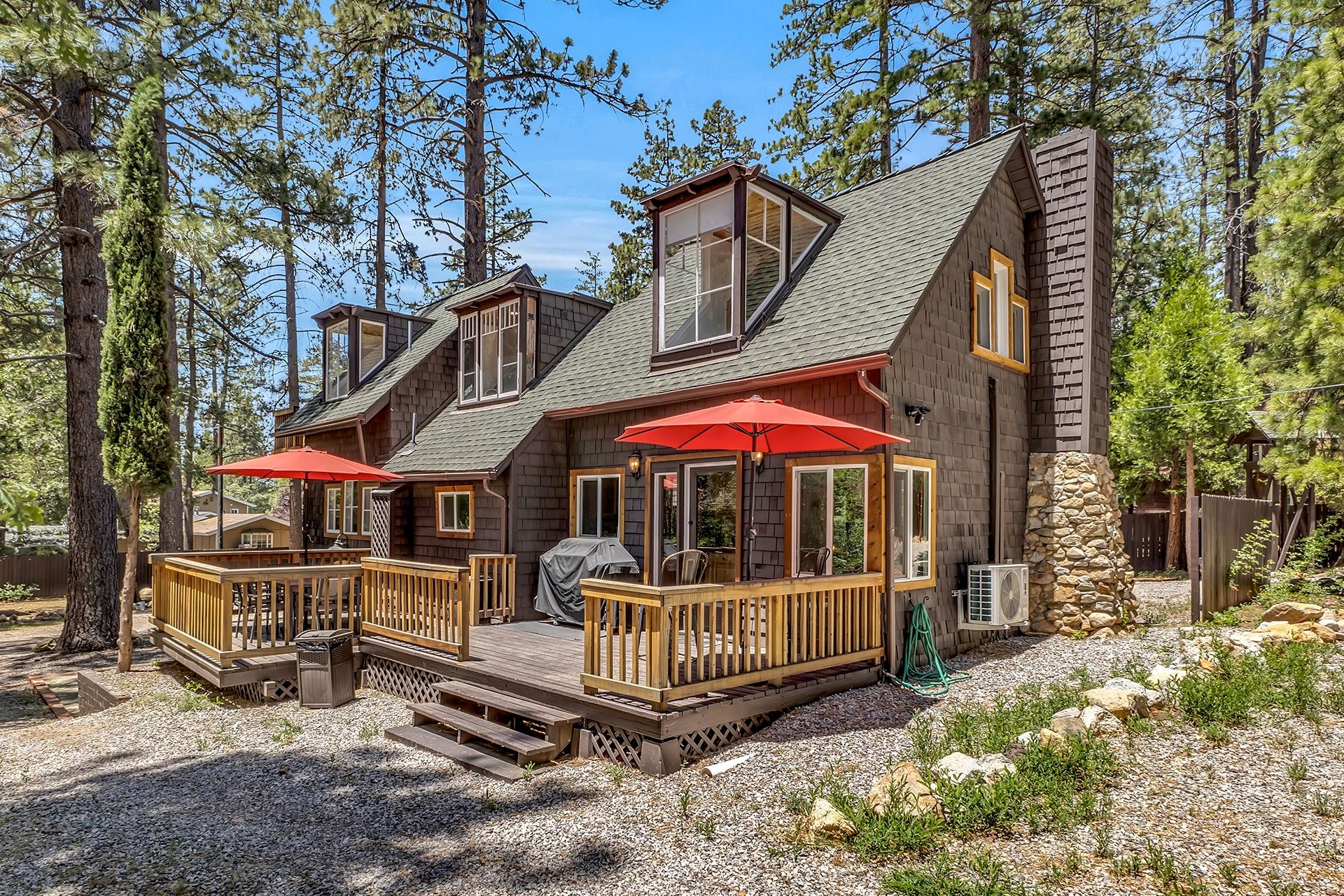 A cabin with a deck, outdoor seating, and a stone chimney.