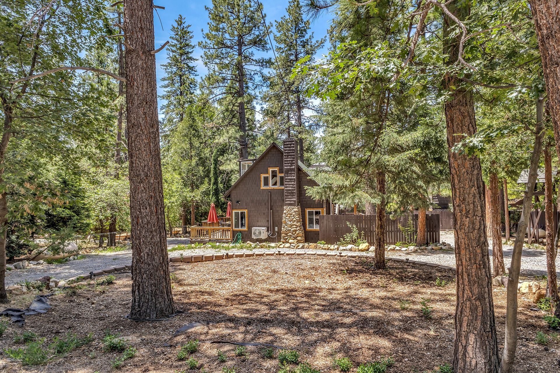 Une cabane entourée de grands arbres, sous un ciel dégagé.
