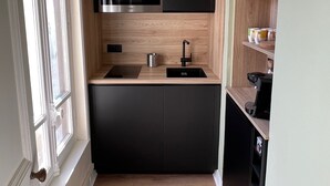 A compact kitchen with black cabinets, a stainless steel microwave, and a coffee machine.