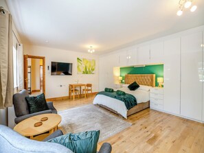 A modern hotel room with a bed, a TV, a desk, and a sofa.