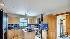 Une cuisine moderne avec des meubles en bois, un îlot central et une vue sur l’extérieur.