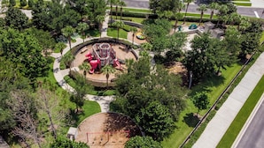 Vue aérienne d’un parc avec des jeux pour enfants, une piste circulaire et de la végétation luxuriante tout autour.