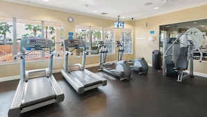 Une salle de sport équipée de tapis de course, de vélos elliptiques et de matériel de musculation.