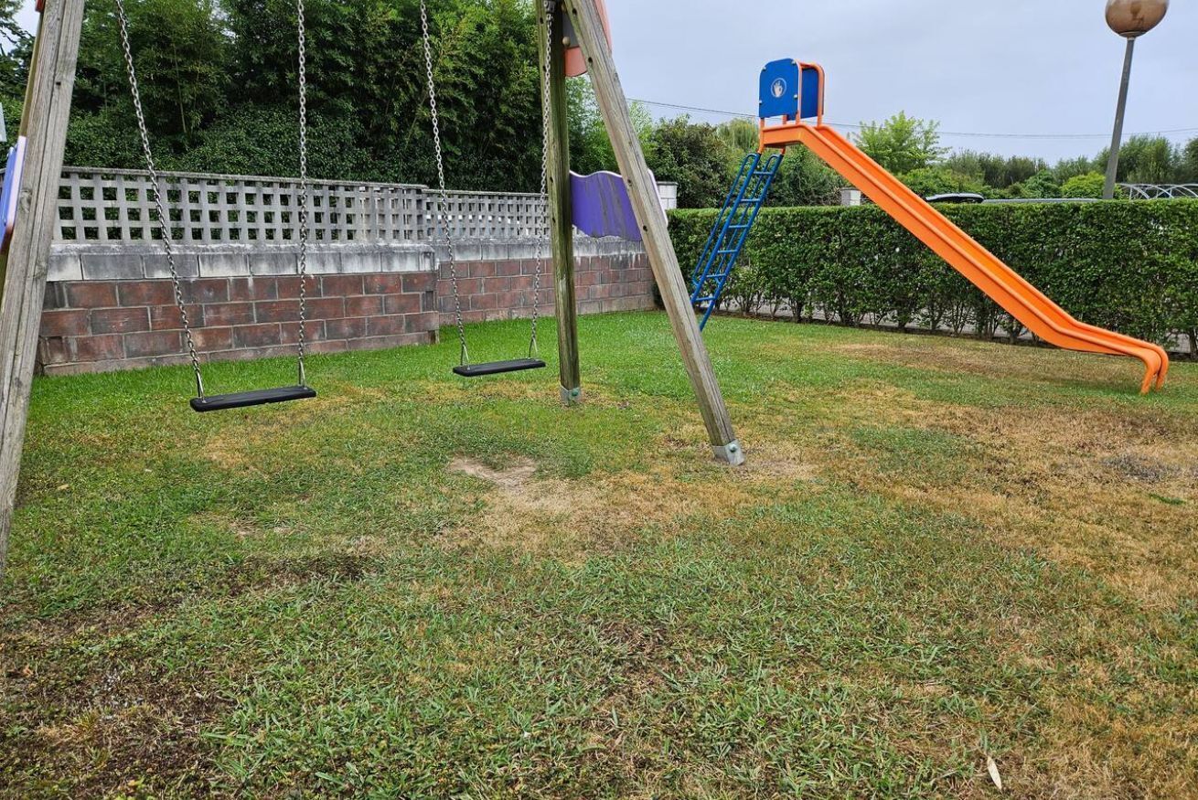 Een speeltuin met schommels en een glijbaan.