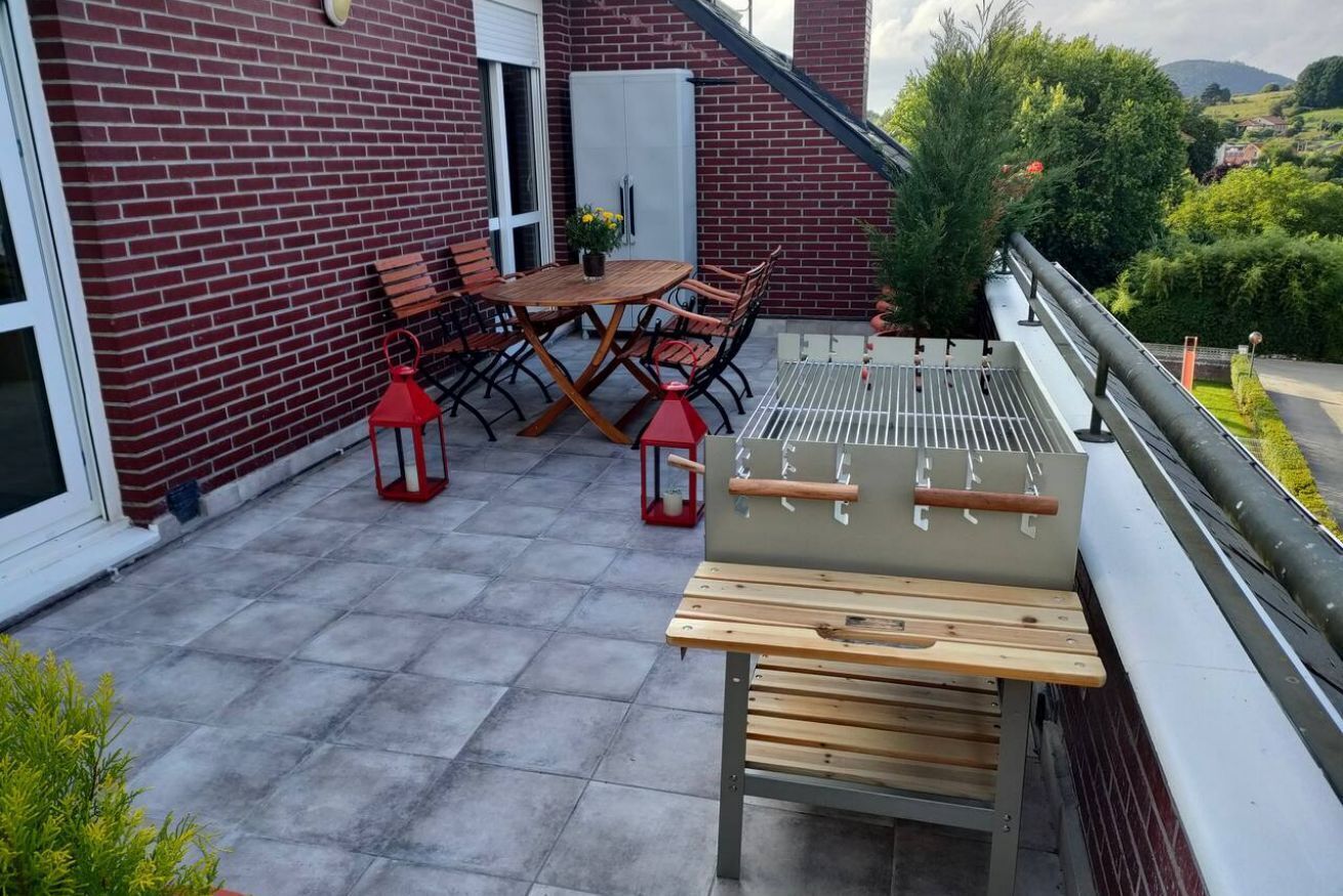 Eine Terrasse mit Tisch und Stühlen, einem Grill und einem roten Laternen