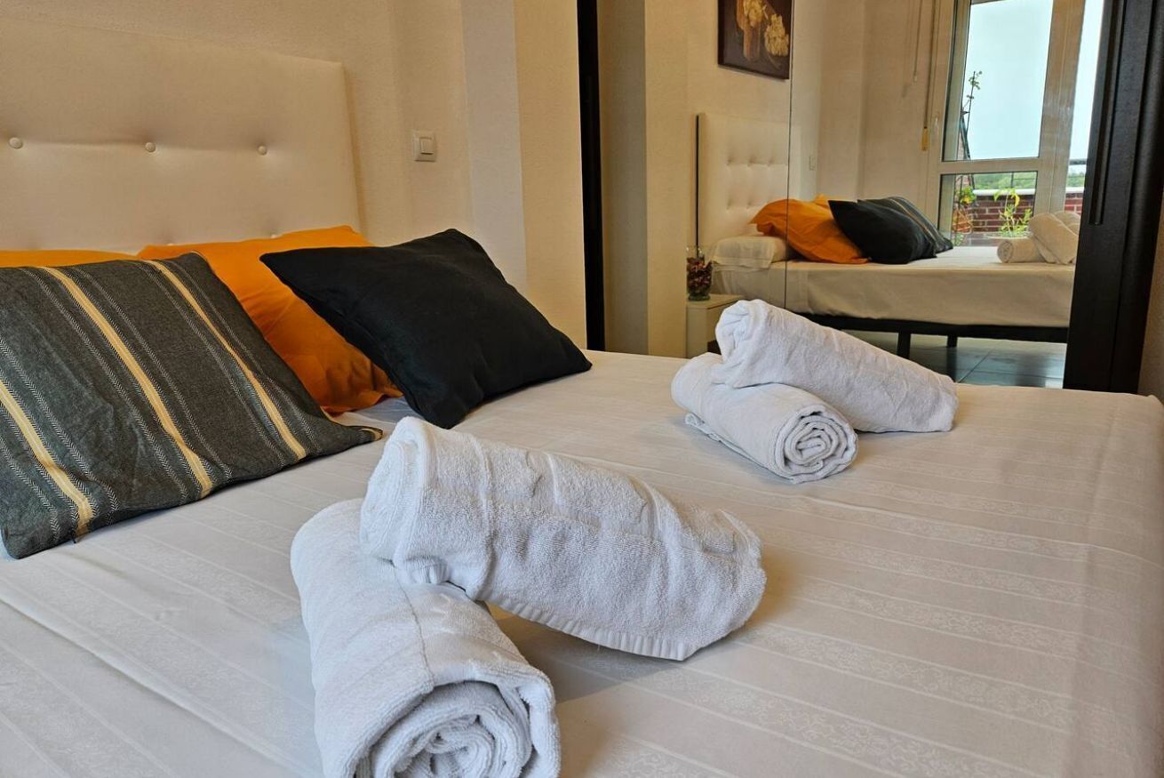 Et hotelværelse med en seng, puder og håndklæder.