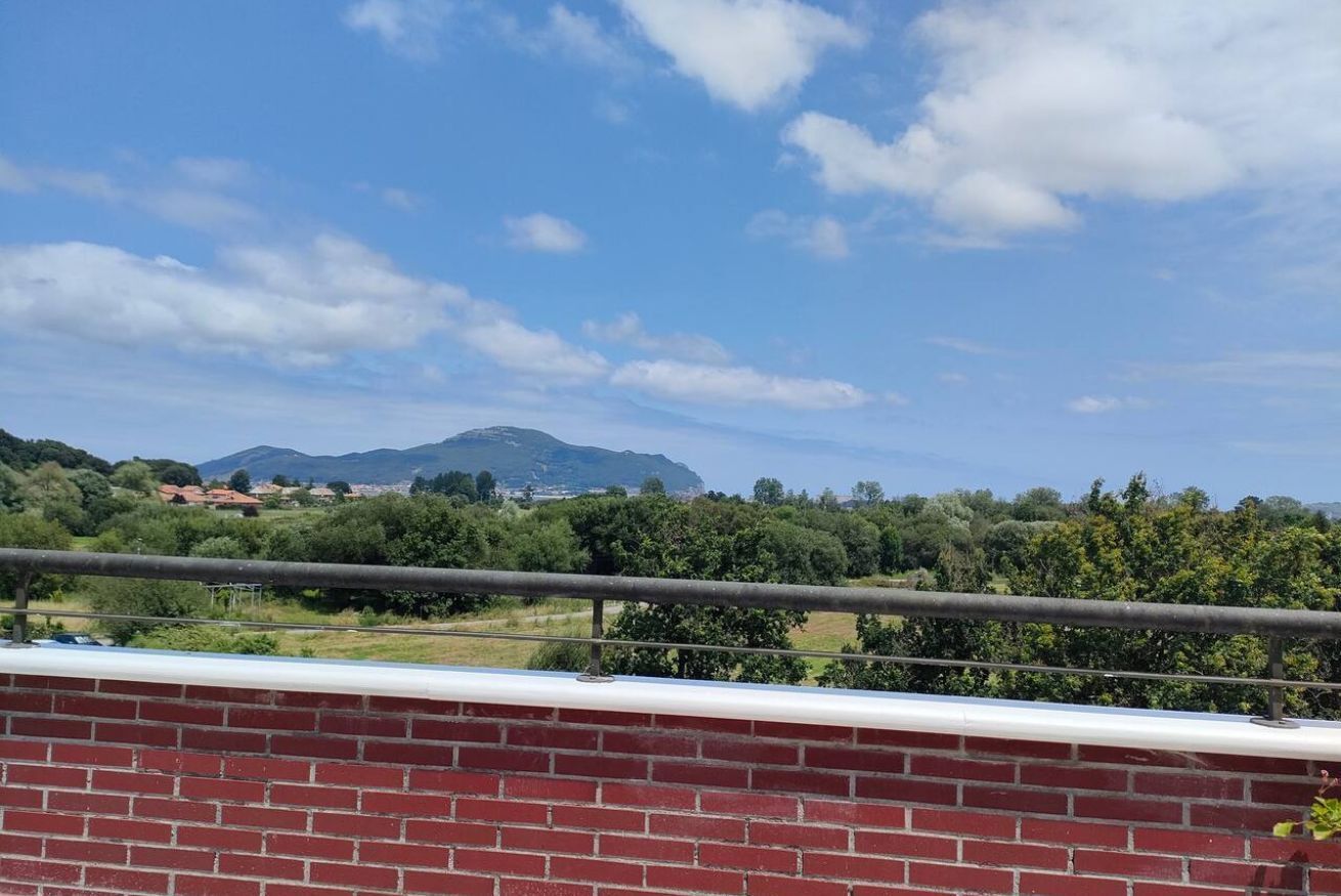 Vista de un paisaje montañoso con cielo despejado y un muro de ladrillo al frente.