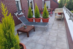 Un patio con una silla de descanso, una mesita y plantas en macetas.