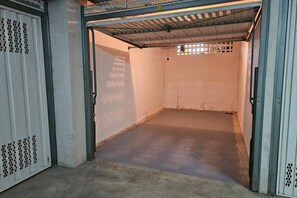 Una habitación con suelo de concreto, techo metálico y una puerta blanca con un diseño decorativo.