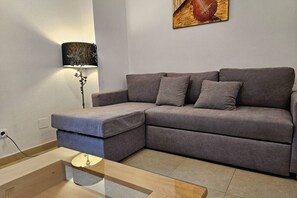 Una sala de estar moderna con un sofá seccional gris, una lámpara de pie y un cuadro en la pared.