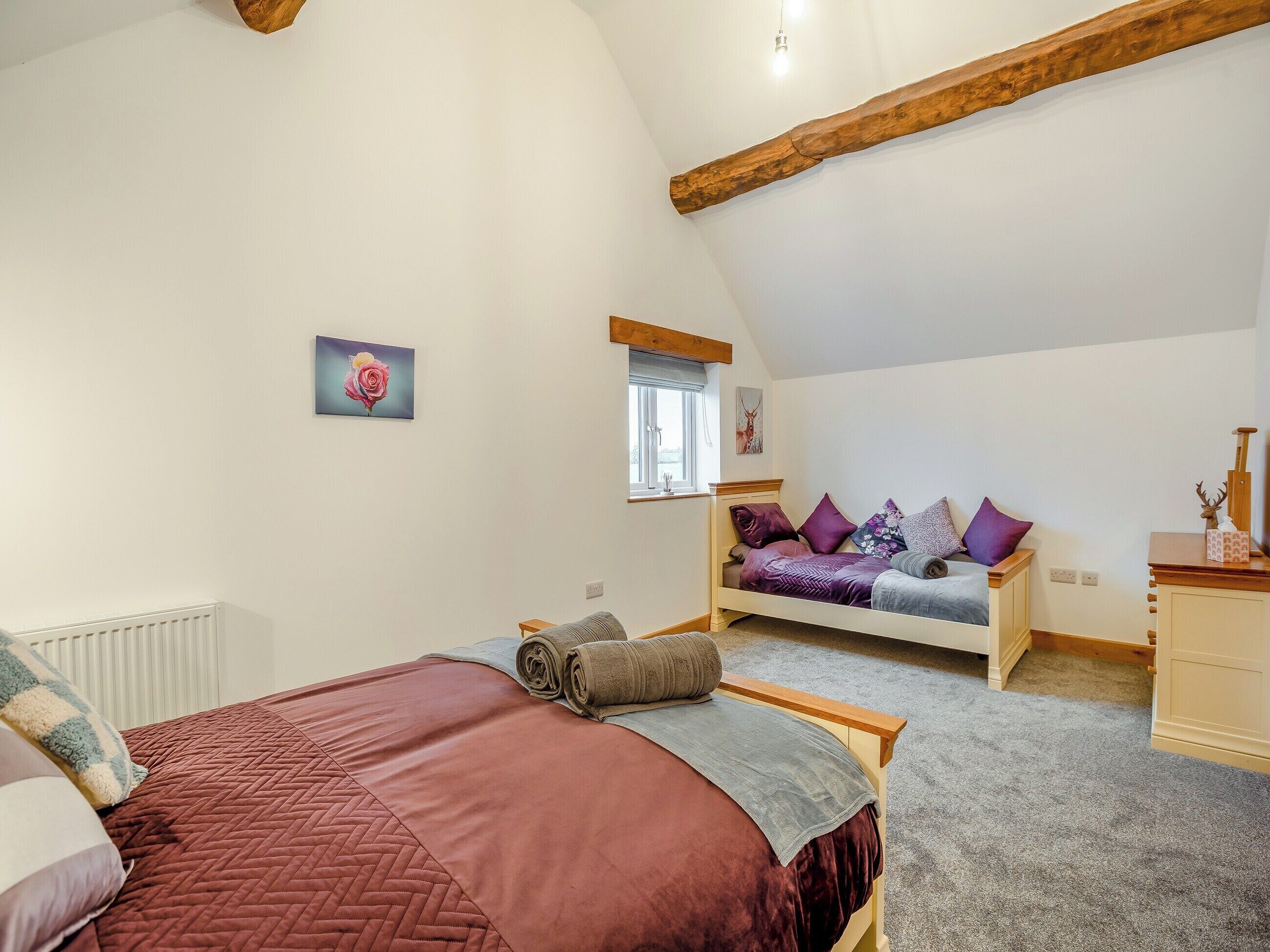 Een slaapkamer met een bed, een raam, een dressoir en een schilderij aan de muur.