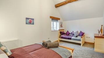 Een slaapkamer met een bed, een raam, een dressoir en een schilderij aan de muur.