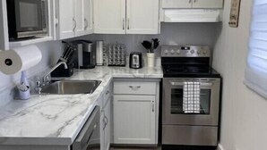 A compact kitchen with white cabinets, a stainless steel stove, and a microwave. - Center City with Recent Renos
(King & Double Beds) (St. John's)