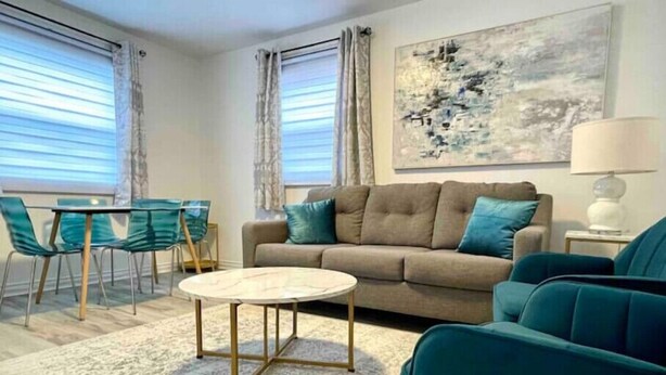 A living room with a sofa, two chairs, a coffee table, and a painting on the wall. - Center City with Recent Renos
(King & Double Beds) (St. John's)