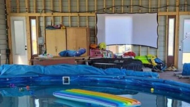 A swimming pool with a rainbow float, surrounded by a blue pool cover. - The Cricket Cabin Bathroom sep building (Kempner)