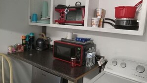 A kitchen with a microwave, kettle, and a washing machine. - The Cricket Cabin Bathroom sep building (Kempner)