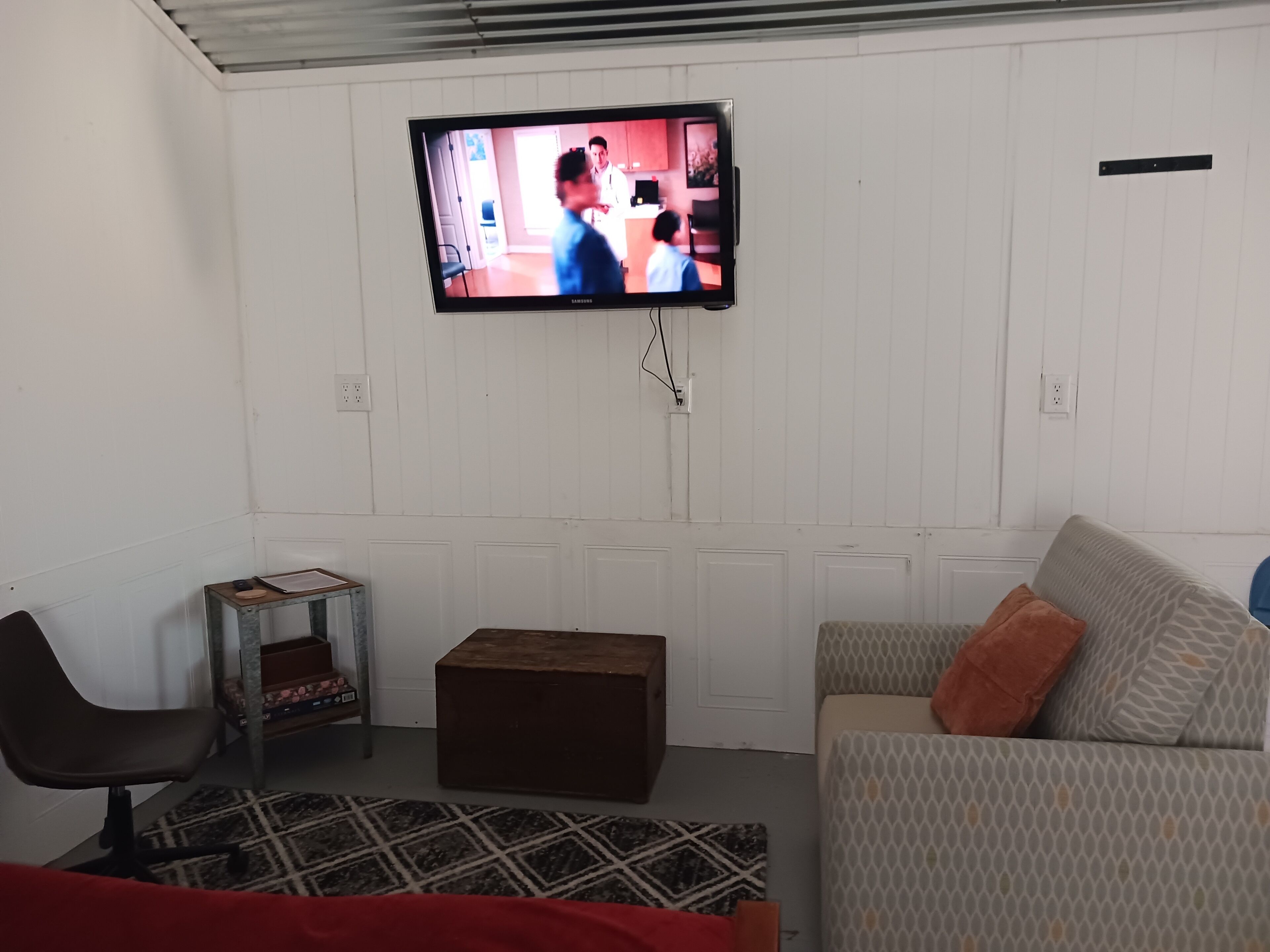 A living room with a television mounted on the wall, a sofa, a coffee table, and a chair.