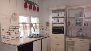 Una cocina con armarios blancos, un lavavajillas negro, un microondas y un fregadero.