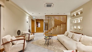 Una sala de estar moderna con un sofá, sillones, una mesa de centro y una estantería.