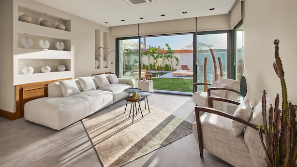 Una sala de estar moderna con un ventanal grande, un sofá, una mesa de centro y objetos decorativos en estanterías.