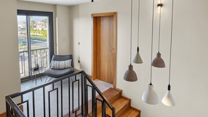 Una escalera de madera con barandilla de cristal que da a un balcón con vistas al exterior.