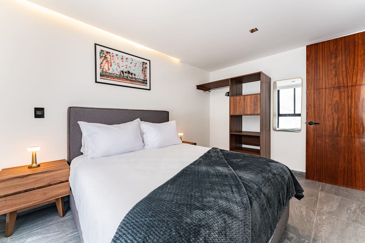 A modern bedroom with a bed, wooden nightstand, and a wardrobe.