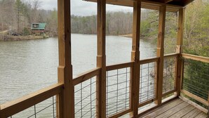 A wooden deck with a view of a lake and a house in the background. - Boo Bear: New luxe lakeside cabin, hottub, caves, fast Wifi @ BearTrackLake (Beattyville)